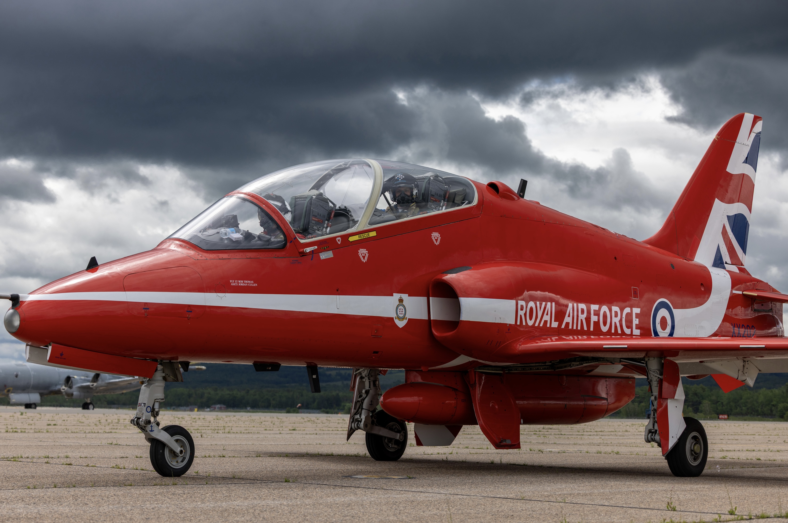A single Red Arrows jet is parked on the ground, under very gloomy grey skies.