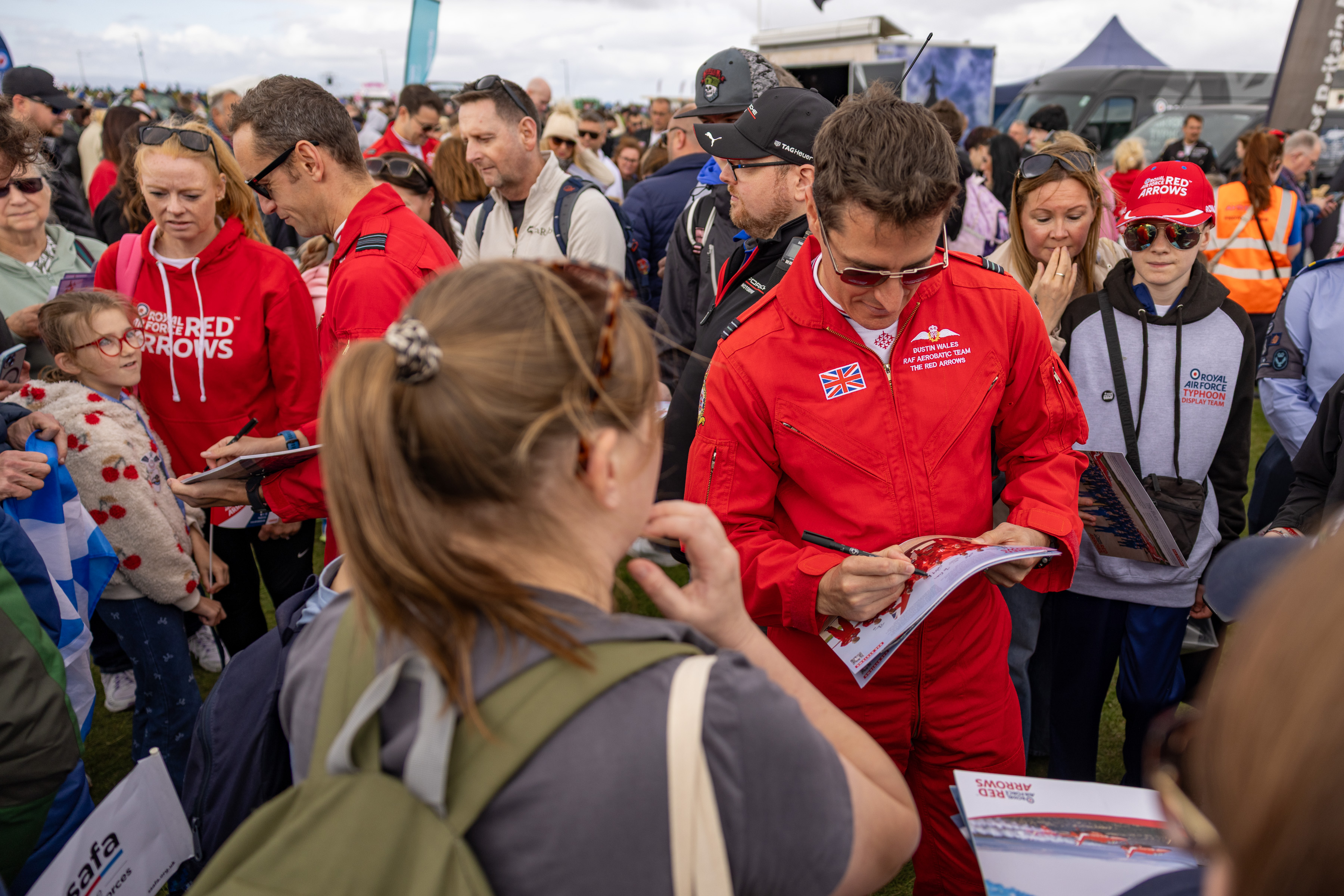 Crowds at an airshow in Scotland meet the Red Arrows pilots and get autographs.