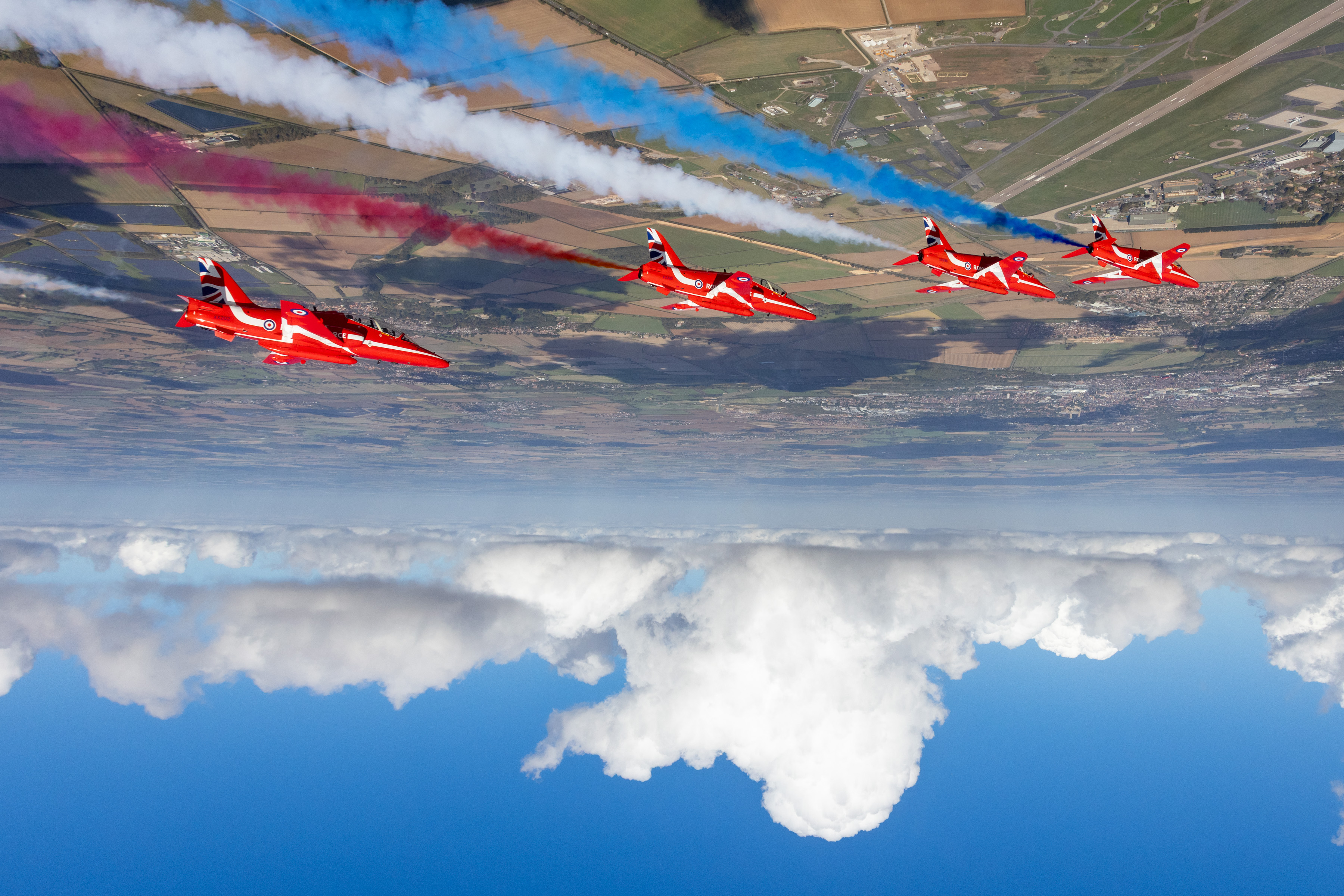 Four Red Arrows jets fly upside down with red, white and blue coloured trails.