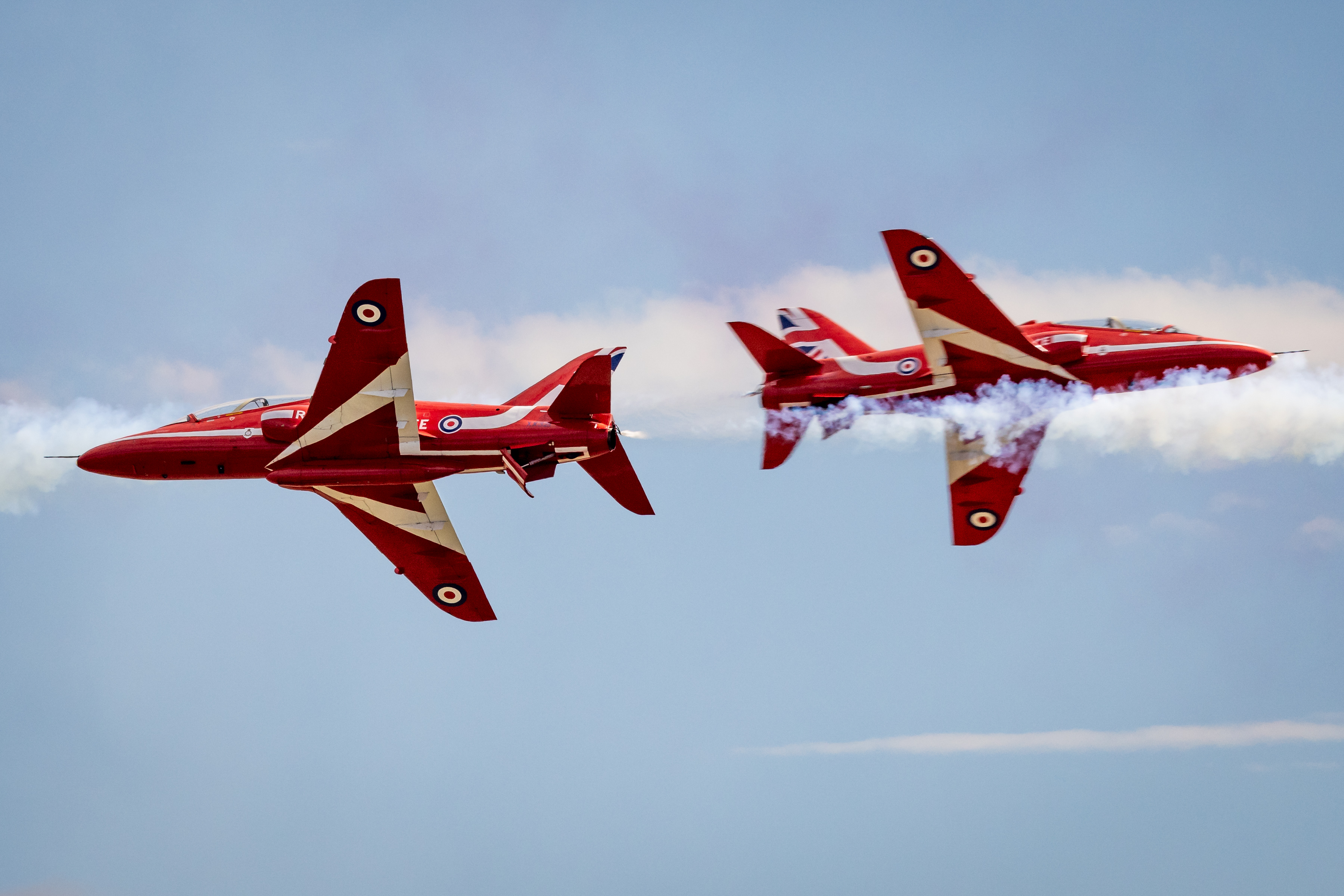 Two Red Arrows jets pass one another in close proximity.