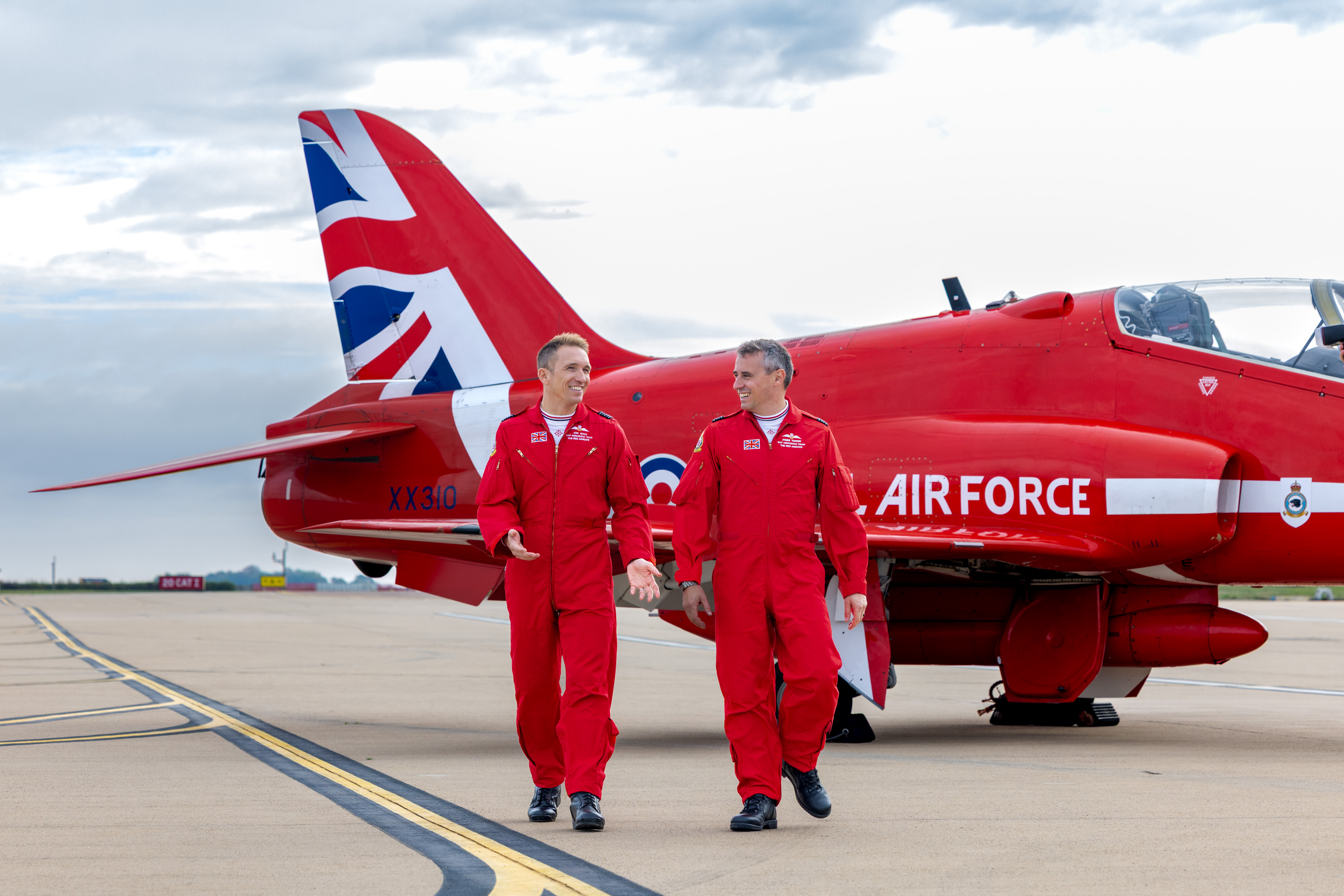 Wing Commander Jon Bond, the previous Red 1, walks away from a Hawk jet with new Team Leader, Squadron Leader James Turner, on this left at RAF Waddington.