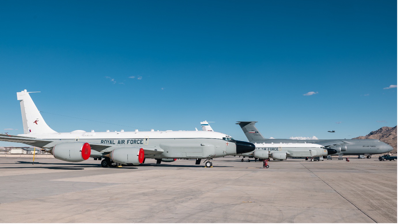 Two RAF Rivet Joint aircraft parked on the runway alongside aircraft from the US Air Force during daytime.