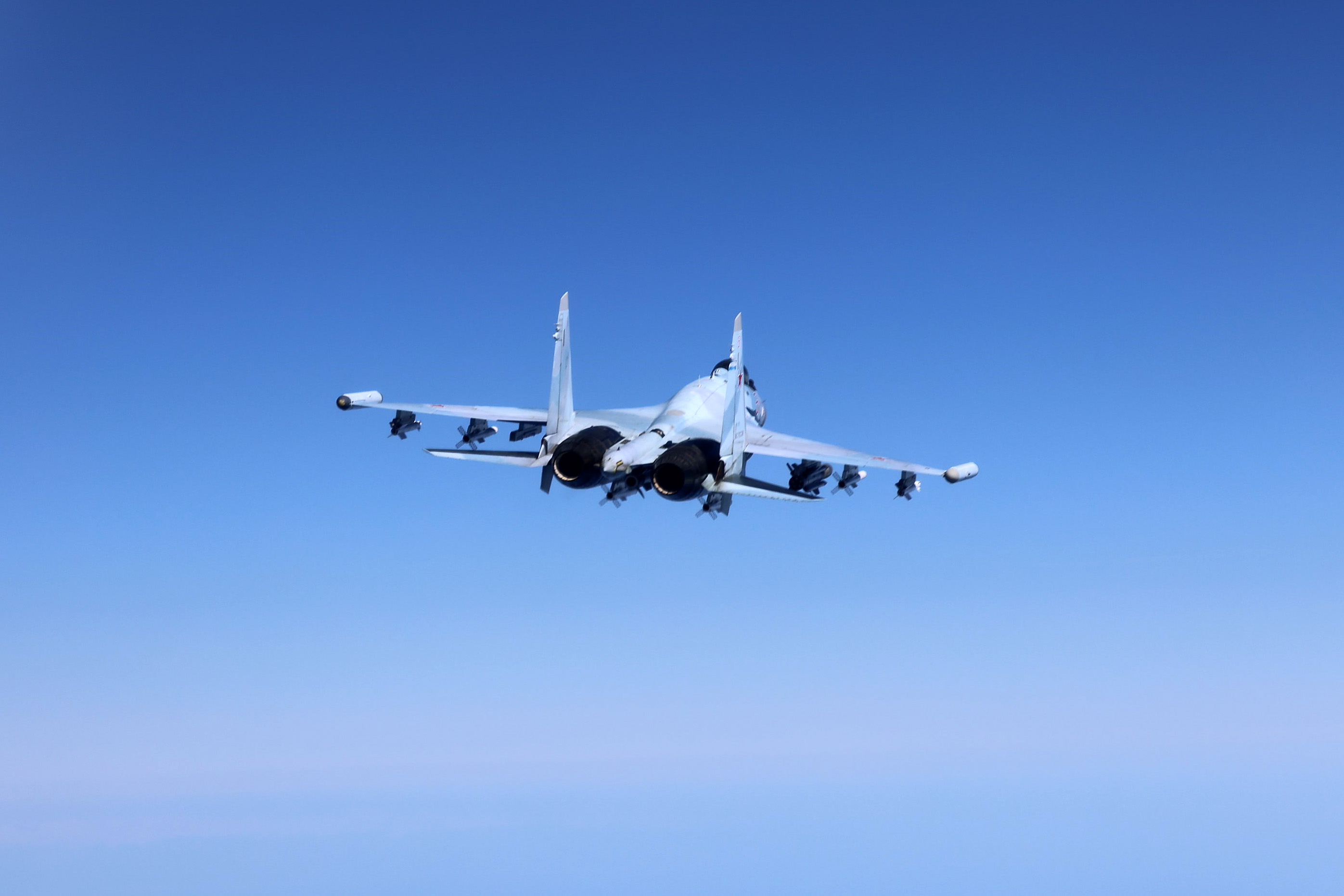 A Russian aircraft pictured dangerously close to an RAF Rivet Joint over the Black Sea, with blue skies in the background.