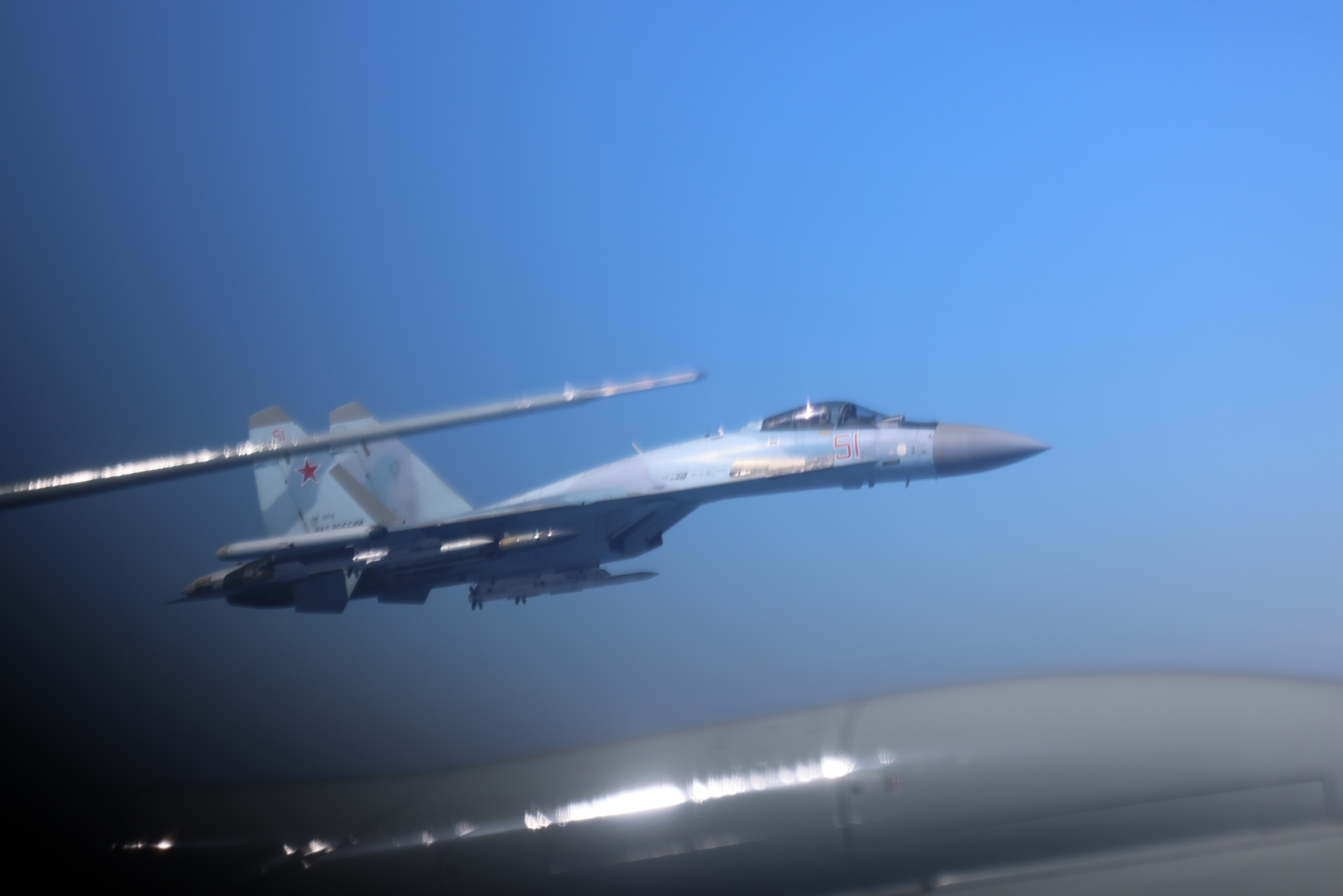 A Russian fighter jet pictured dangerously close to an RAF Rivet Joint's wing, in a display of poor airmanship.