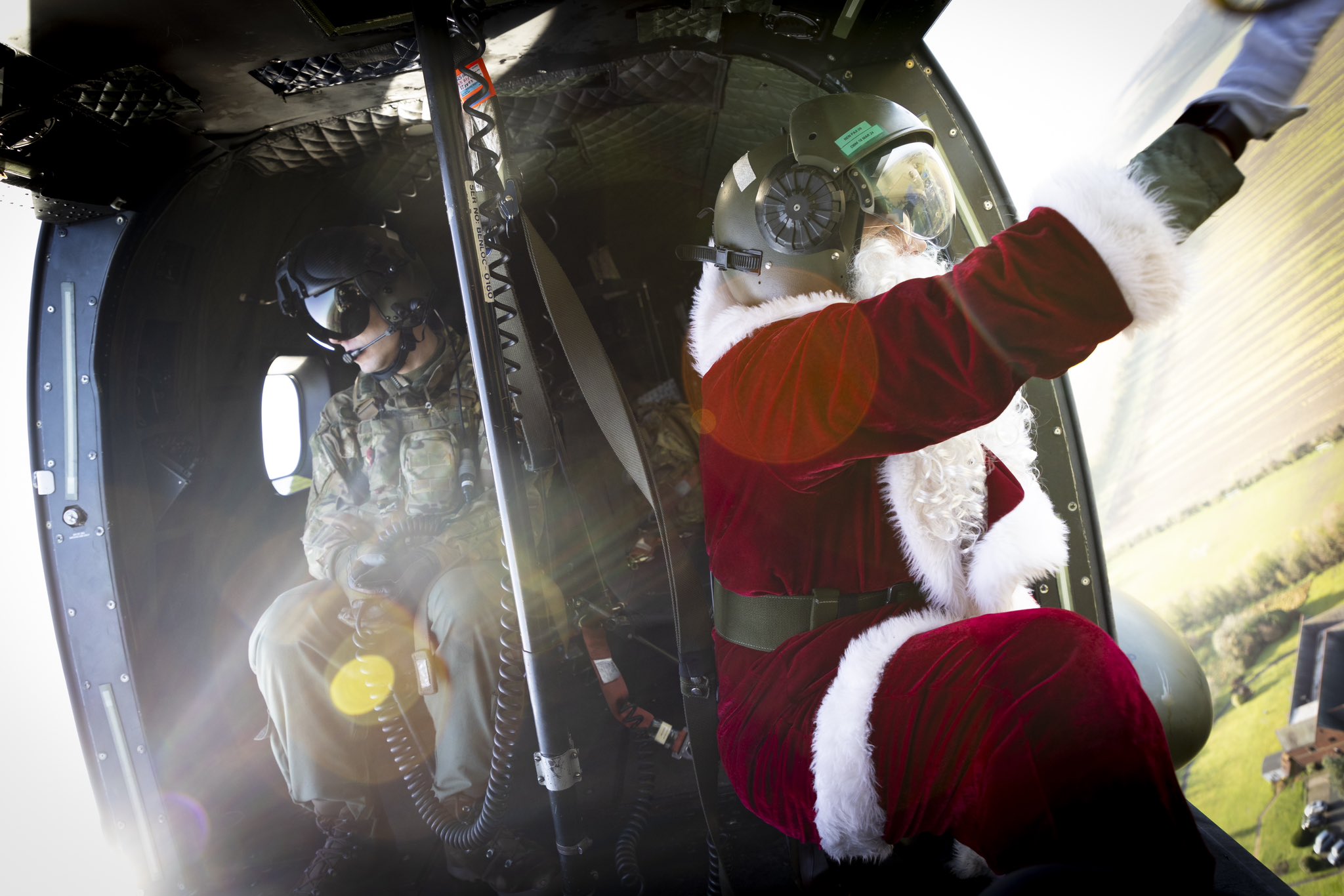 Santa waving at a town from inside a helicopter