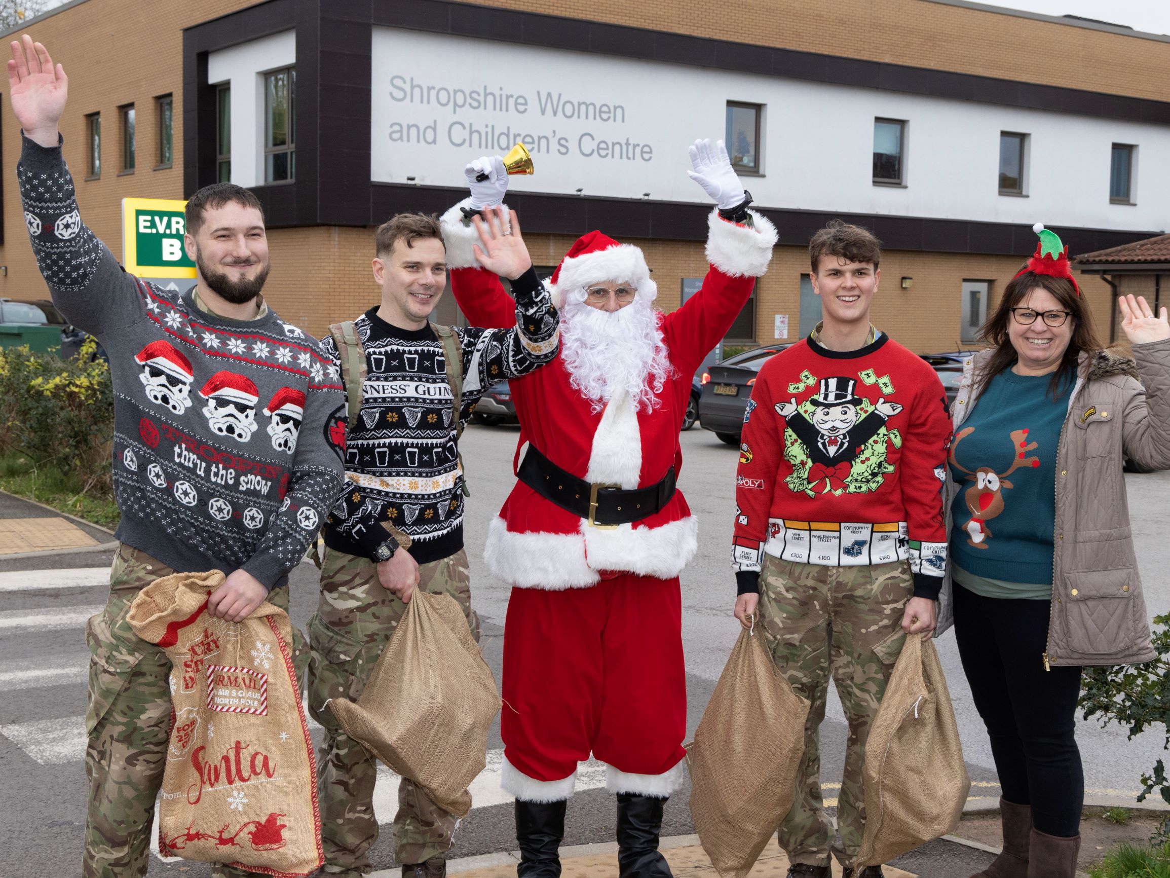 Santa stands with personnel holding sacks.