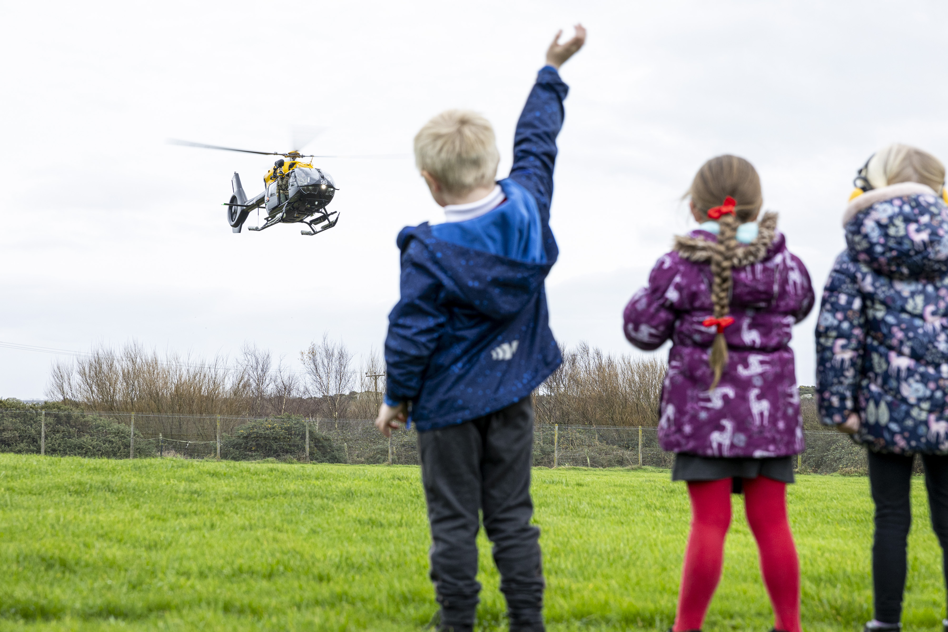 Children wave to helicopter over head.