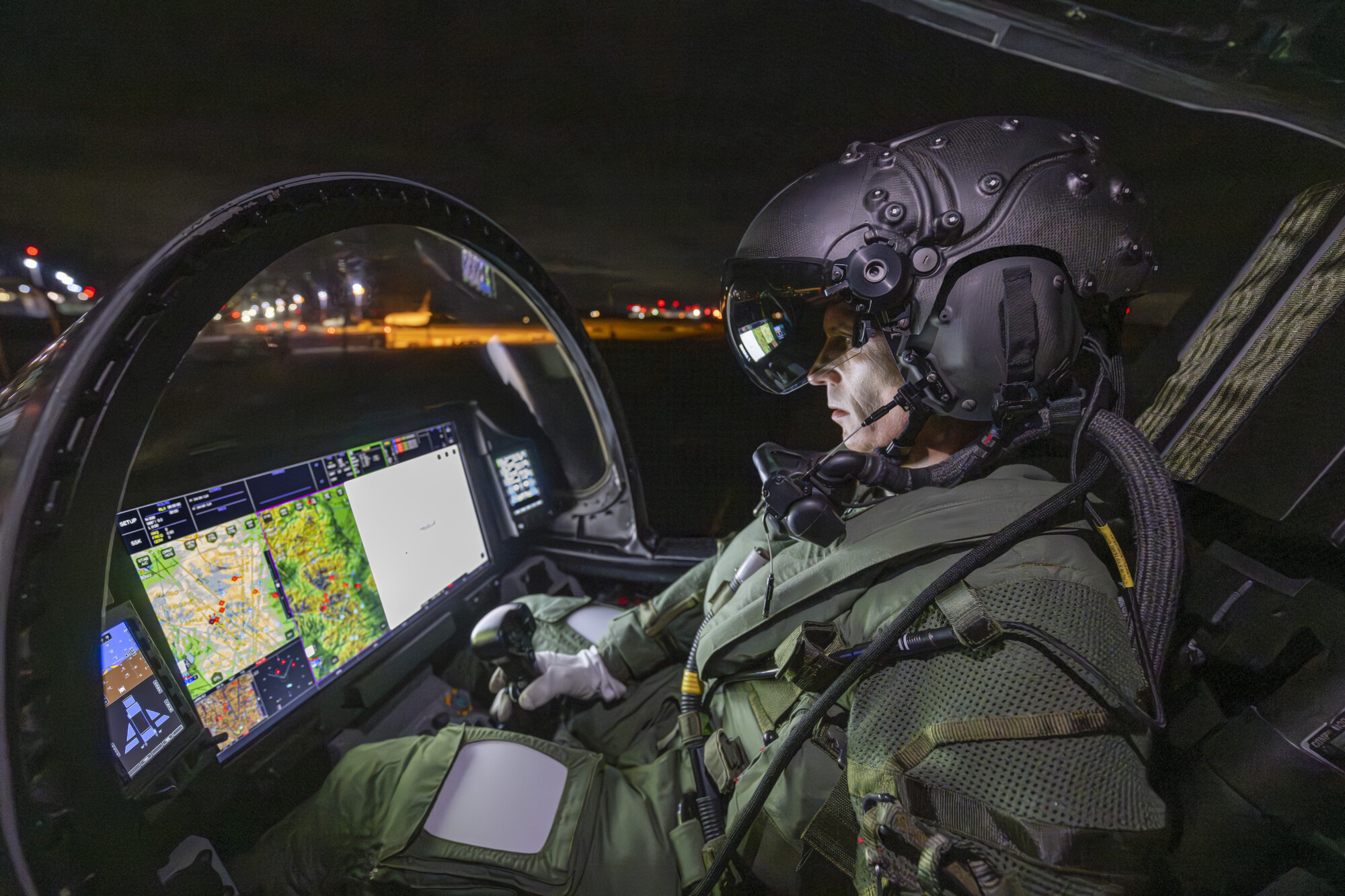 Pilot in aircraft wearing helmet and looking at aircraft screen