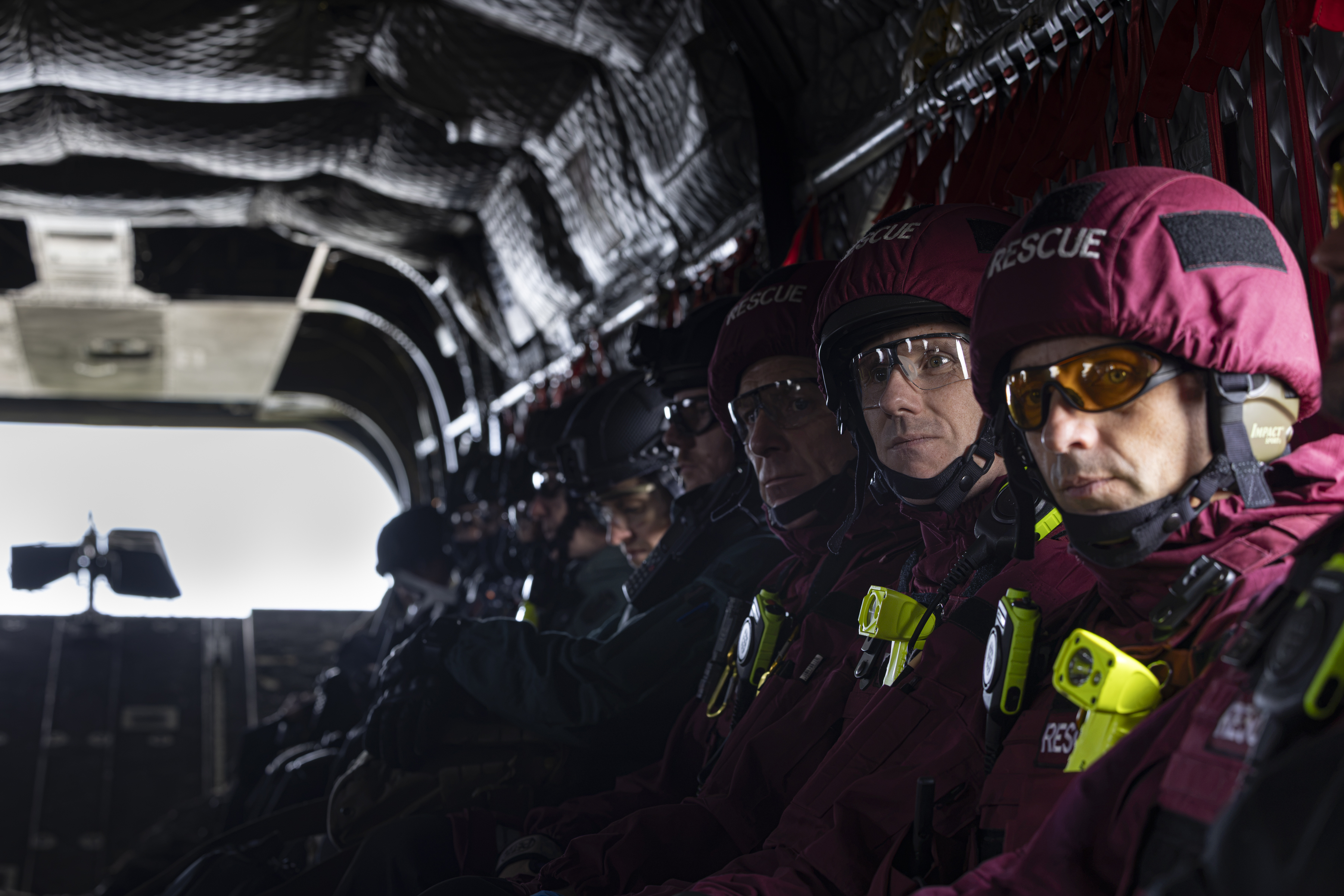 Emergency services and military personnel assembled in the loading bay of an RAF aircraft, preparing for takeoff.
