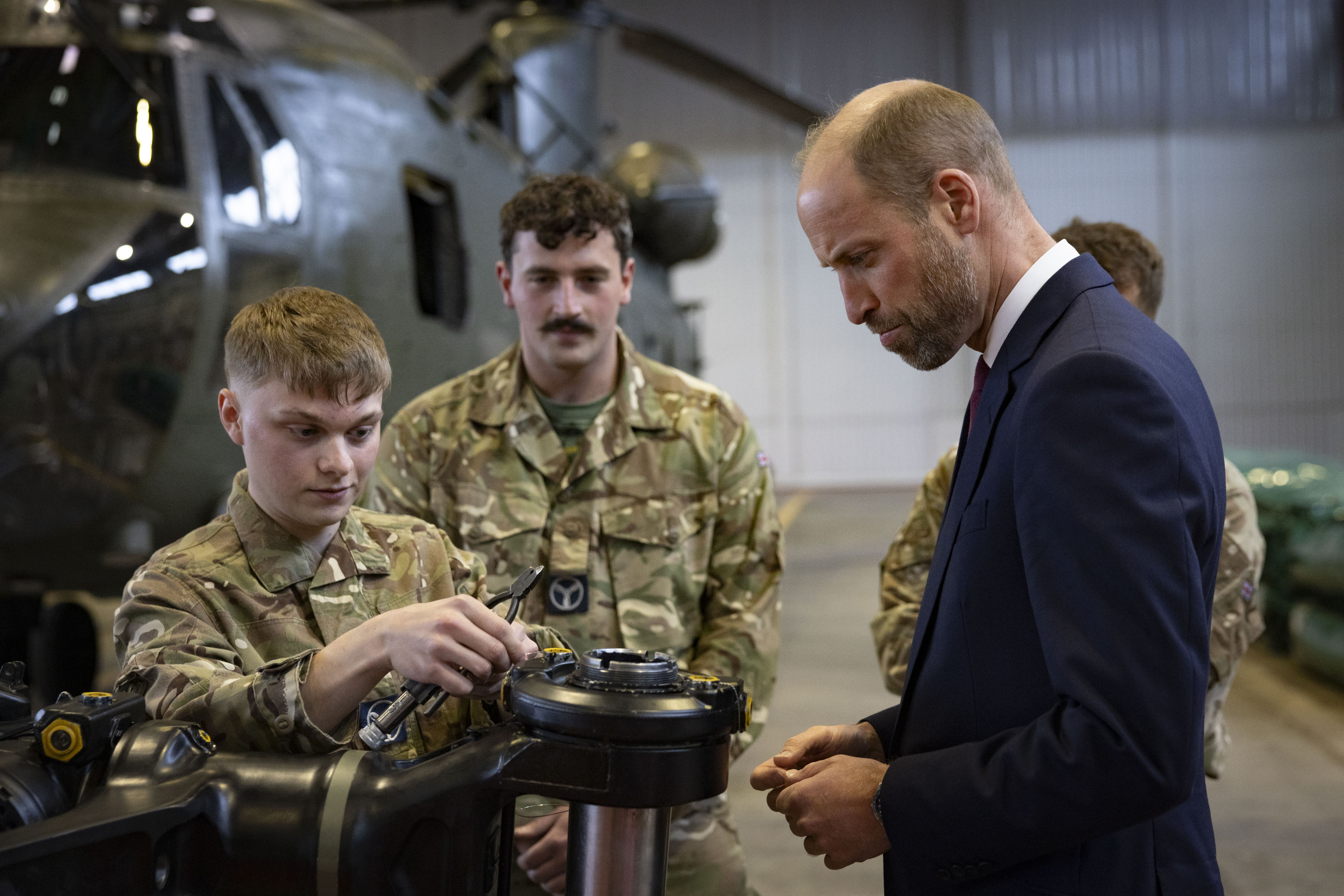 Prince William looks on as a young technician works on a rotor head.