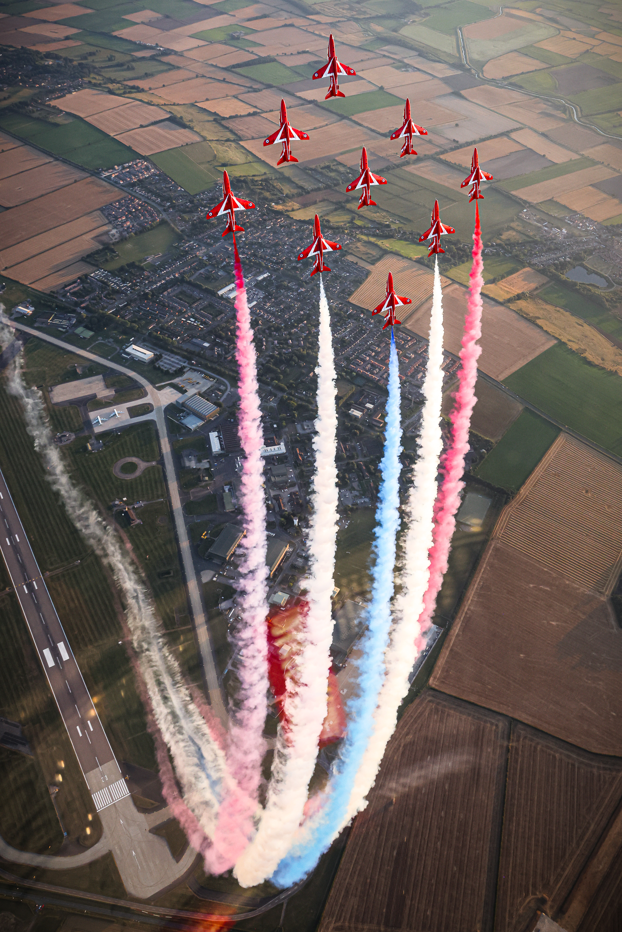 Red Arrows flying upwards, with their signature red, white, and blue smoke trailing behind them.